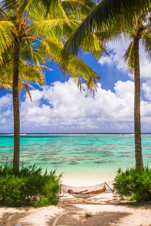 Cook Islands Landscape Travel Photography Woman relaxing in a hammock under palm trees on the white sandy beach on the tropical island of Rarotonga Cook Islands South Pacific Ocean