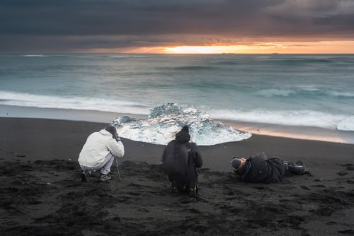 Iceland Landscape Photography Tourists taking a photo of icebergs at sunrise on Jokulsarlon Beach a black volcanic sand beach in South East Iceland Europe