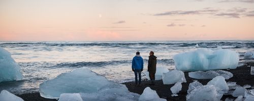 Iceland Travel Photography Father and son walking on Jokulsarlon Beach a black volcanic beach at sunset South East Iceland