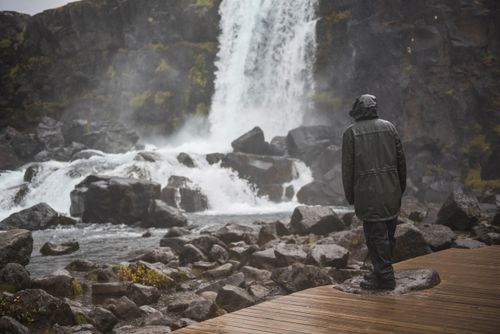 Iceland Travel Photography Man braving torrential rain and bad weather in Thingvellir Pingvellir National Park The Golden Circle Iceland Europe