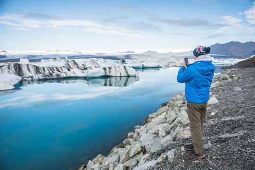 Iceland Travel Photography Tourist at Jokulsarlon Glacier Lagoon a glacial lake filled with icebergs in South East Iceland Europe