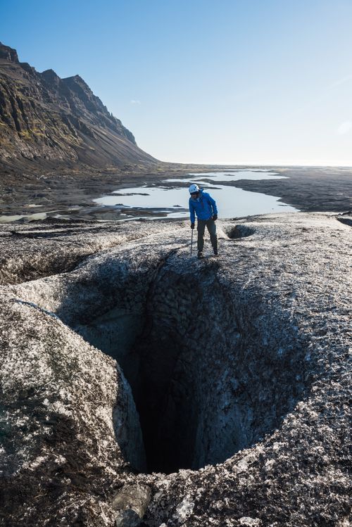 Iceland Travel Photography Tourist peering into a crevasse on Breidamerkurjokull Glacier Vatnajokull Ice Cap Iceland