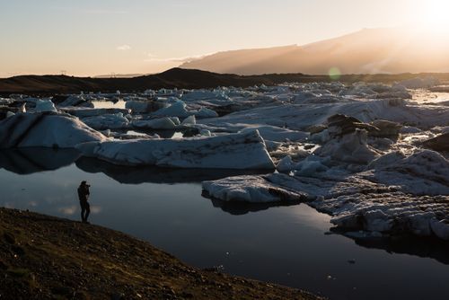 Iceland Travel Photography Tourist taking a photo of icebergs at Jokulsarlon Glacier Lagoon at sunset South East Iceland