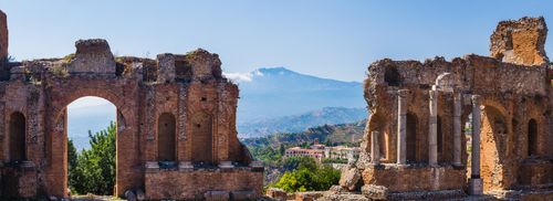 Italy Sicily Travel Photography Panoramic photo of Taormina Greek Theatre aka Teatro Greco ruins of columns at the amphitheatre with Mount Etna Volcano in the background Sicily Italy Europe