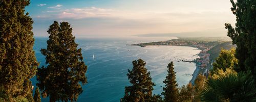 Italy Sicily Travel Photography Taormina on the Sicilian Coast at sunset panoramic photo of Naxos Bay with the foot on Mount Etna Volcano on the right Ionian Sea Mediterranean Sea Sicily Italy Europe