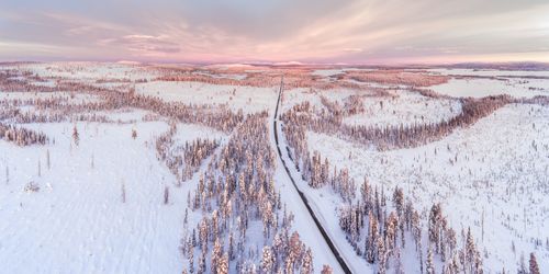 Lapland Finland Drone Landscape Photography Icy snow covered winter road in the Arctic Circle at sunset in Lapland Finland