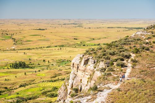 Madagascar Landscape Photography Tourist walking in Isalo National Park with Ihorombe Plains behind Southwest Madagascar