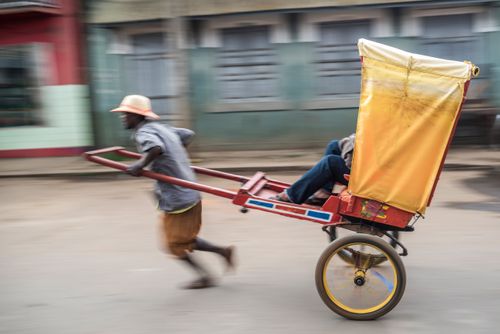 Madagascar Travel Street Photography Man powered rickshaw pousse pousse in Antisrabe Vakinankaratra Region Madagascar Central Highlands