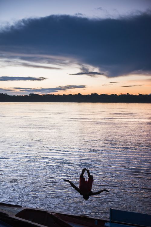 Peru Travel Photography Jumping and playing in the river at sunset in the Tambopata National Reserve Amazon Jungle of Peru South America