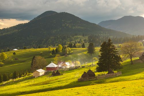 Romania Landscape Travel Photography Farm and haystacks in the rural Transylvania landscape at sunset Piatra Fantanele Transylvania Romania
