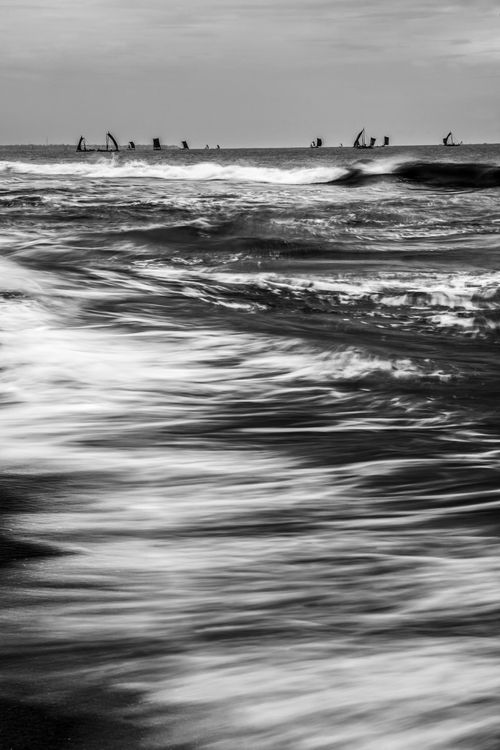 Sri Lanka Travel Photography Black and white photo of traditional Sri Lankan oruva fishing boats returning at sunrise to Negombo fishing market seen from Negombo Beach Sri Lanka Asia