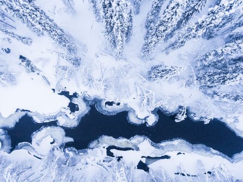 Landscape Photography by Professional Freelance UK Landscape Photographer Aerial of frozen river and snow covered forest winter landscape showing amazing Lapland scenery in Scandinavia in Finland drone